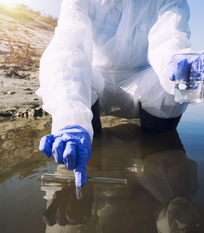 Unrecognizable ecologist taking samples of water with test tube